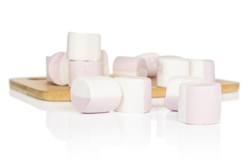 Lot of whole sweet pastel marshmallow on bamboo cutting board isolated on white background