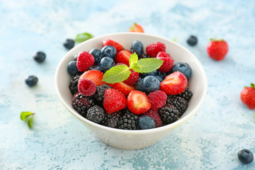 Bowl with tasty berry salad on color background