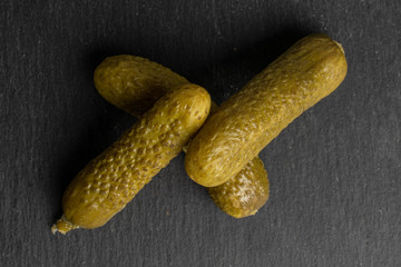 Group of three whole sour green pickle flatlay on grey stone