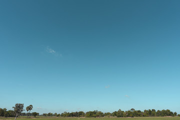 Blue sky background with green fields and white clouds.