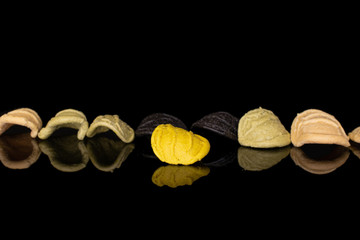 Group of eight whole colorful pasta orecchiette isolated on black glass