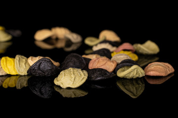 Lot of whole disordered colorful pasta orecchiette isolated on black glass