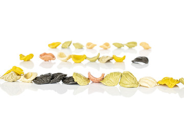 Lot of whole colored colorful pasta orecchiette in row isolated on white background