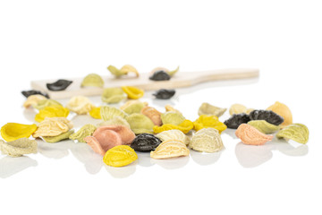 Lot of whole colorful pasta orecchiette on wooden cutting board isolated on white background