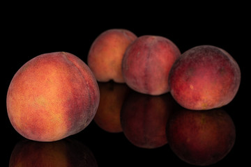 Group of four whole sweet red peach isolated on black glass