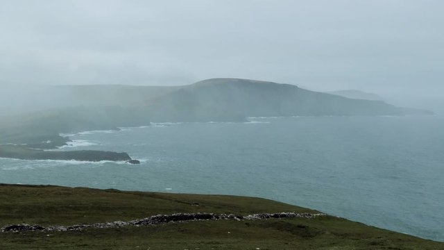 footage of bray head on the ring of kerry in the south coast of ireland on a stormy day showing battering waves and green grass on rocky coastline