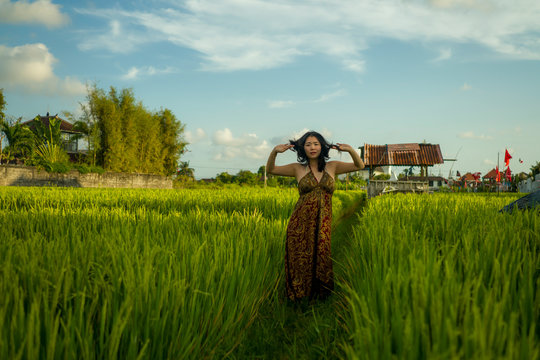 young happy and beautiful Asian woman enjoying nature at rice field. sweet Korean girl exploring countryside during holiday travel in wanderlust and tourism concept
