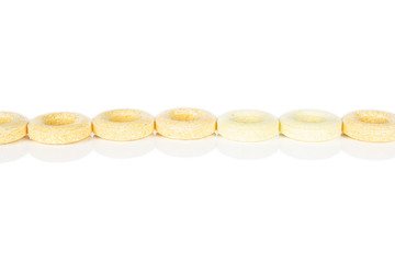 Lot of whole round pale yellow candy in line isolated on white background