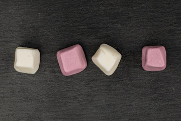 Group of four whole soft pastel candy flatlay on grey stone