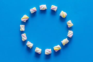 Pastel marshmallows background. Round shaped set of sweets on blue table top view mockup copy space