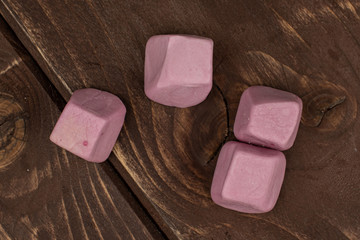 Group of four whole soft pastel candy flatlay on brown wood