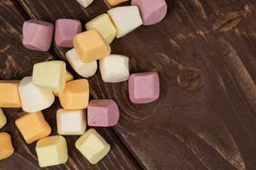Lot of whole disordered soft pastel candy flatlay on brown wood