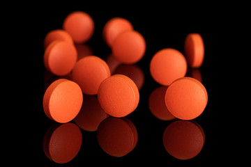 Group of eleven whole orange tablet pharmacy isolated on black glass