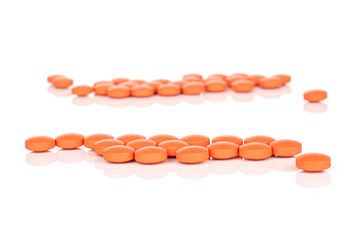 Lot of whole orange tablet pharmacy in row isolated on white background