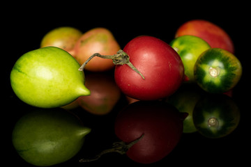 Group of seven whole fresh tomato de barao isolated on black glass