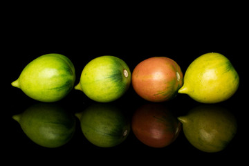 Group of four whole fresh tomato de barao in row isolated on black glass