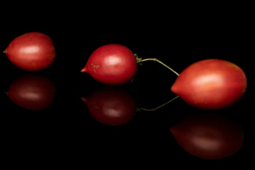 Group of three whole fresh tomato de barao diagonal isolated on black glass