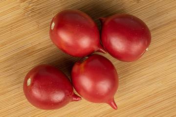 Group of four whole fresh tomato de barao flatlay on light wood