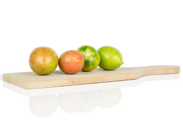 Group of four whole fresh tomato de barao on wooden cutting board isolated on white background