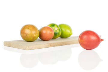 Group of five whole fresh tomato de barao on wooden cutting board isolated on white background