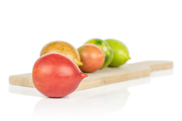 Group of five whole fresh tomato de barao on wooden cutting board isolated on white background