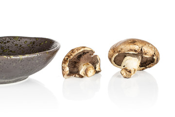 Group of two whole fresh brown mushroom champignon on glazed bowl isolated on white background