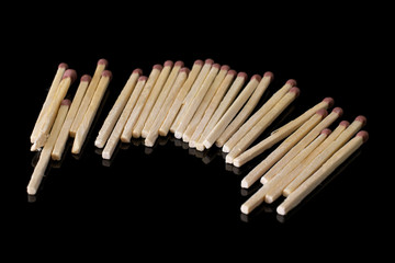 Lot of whole wooden brown safety match isolated on black glass