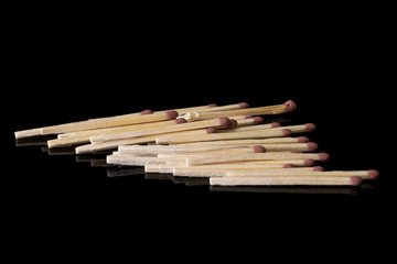 Lot of whole brown safety match heap isolated on black glass
