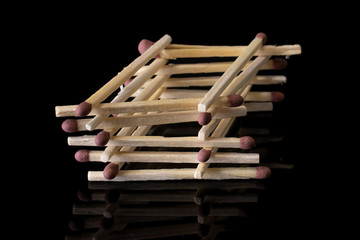 Lot of whole brown safety match tower isolated on black glass