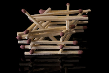 Lot of whole brown safety match tower isolated on black glass