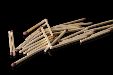 Lot of whole wooden brown safety match heap isolated on black glass