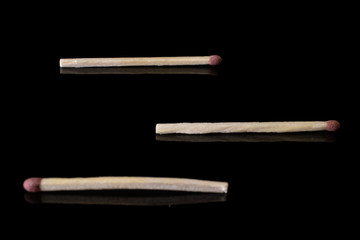 Group of three whole brown safety match isolated on black glass