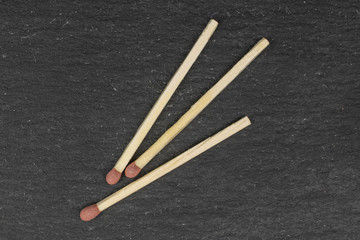Group of three whole brown safety match flatlay on grey stone