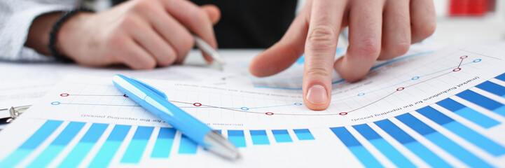 Male arm hold silver pen and point finger in financial graph
