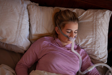 Young person sleeping with nasal pillow cpap machine