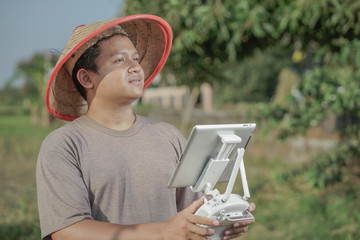 Asian farmers oversee his fields with sophisticated technology