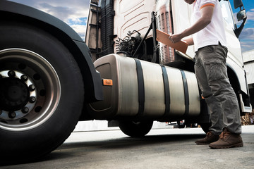Truck driver hand holding clipboard his inspecting safety tank fuel of a semi truck, freight...