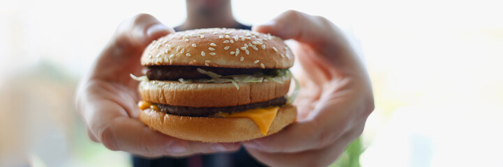 Satisfied young man holding a hamburger