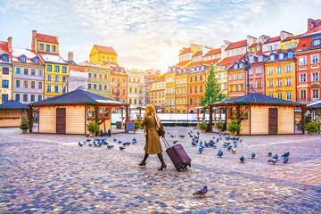 Traveler young woman walking with luggage on the Old Town Square with the Christmas market in...