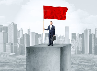 Handsome businessman on the top of the city with red flag