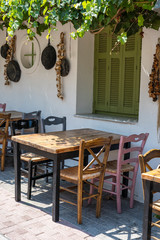 Front view of small cafe exterior. Table and empty chairs outdoor near the white wall. Tourist places. Typical Mediterranean restaurant, a place holidays in the summer