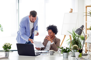 Two business people work in office together with laptop in front