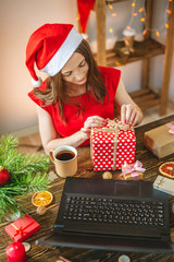 Woman in a red dress receives a gift via the Internet for the New year. Online shopping for Christmas holidays.