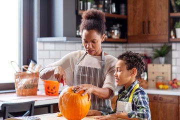 Fototapeta na wymiar Woman with his son at the kitchen prepare pumpkin for halloween