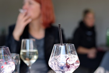 Elegant glass with cocktail in front of mature woman - woman smoking