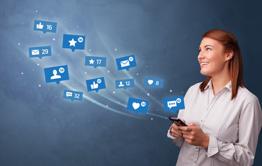 Young person using phone with flying social media icons around