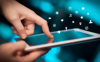 Hand holding tablet with multimedia and application symbols concept