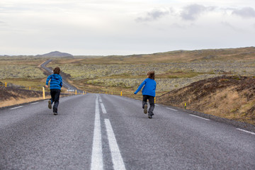 Kids running on an empty road in beautiful nature in Snaefellsjokull National Park in Iceland, autumntime