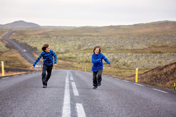 Obraz premium Kids running on an empty road in beautiful nature in Snaefellsjokull National Park in Iceland, autumntime