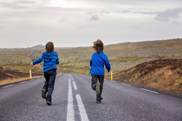 Fototapeta premium Kids running on an empty road in beautiful nature in Snaefellsjokull National Park in Iceland, autumntime